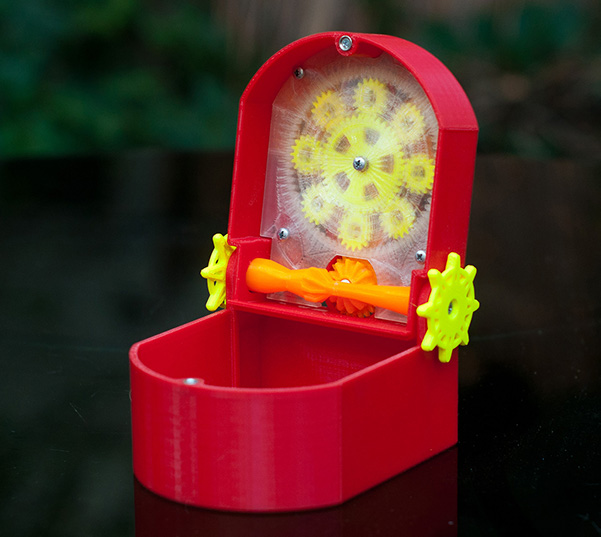 view of the open box - click for larger image open mechanical box in red, yellow, and orange, showing gears attached to the underside of the lid